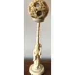 An early 20thC ivory figure, 23cms h with carved concentric ball to top.