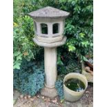 A reconstituted stone octagonal stone birdhouse on stand.