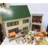 A large 1950's wooden dolls house with tinplate windows and a side building with a quantity of