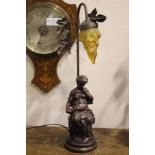 A TABLE LAMP, in the form of a seated lady reading a book, with foliage detail to the base, 22" tall