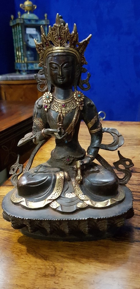 A BRONZE & POLISHED BRASS STATUE OF A SEATED HINDU DIETY, with inset stones, 12" tall approx