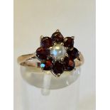 A 9CT YELLOW GOLD GARNET & PEARL DRESS RING, set with 8 faceted garnet stones, and a central