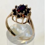 A 9CT YELLOW GOLD, HALLMARKED GARNET CLUSTER RING, with large oval garnet surrounded by 10 round