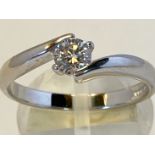 AN 18CT WHITE GOLD DIAMOND SOLITAIRE TWIST RING, set with a quarter carat round brilliant cut