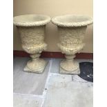 A PAIR OF STONE GARDEN URNS with foliage and floral body having decorative head detail to the