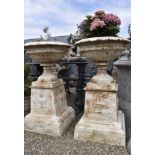 A PAIR OF WHITE CAST IRON GARDEN URNS ON PEDESTAL STANDS