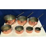 A SET OF 7 COPPER SAUCEPANS, each with a brass handle