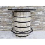 A SOLID OAK BARREL SHAPED BAR TABLE, with metal bands and foot rest