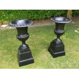 A GOOD QUALITY PAIR OF HEAVY CAST IRON VICTORIAN STYLE GARDEN URNS ON STANDS, black in colour,
