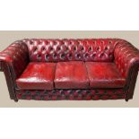 A 3 SEATER OXBLOOD LEATHER CHESTERFIELD COUCH, with roll over back and arm rests, button detail,