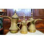 THREE BRASS 'DALLAH' POTS, each with hinged lids, having a sharply pointed beak-shaped spout, and