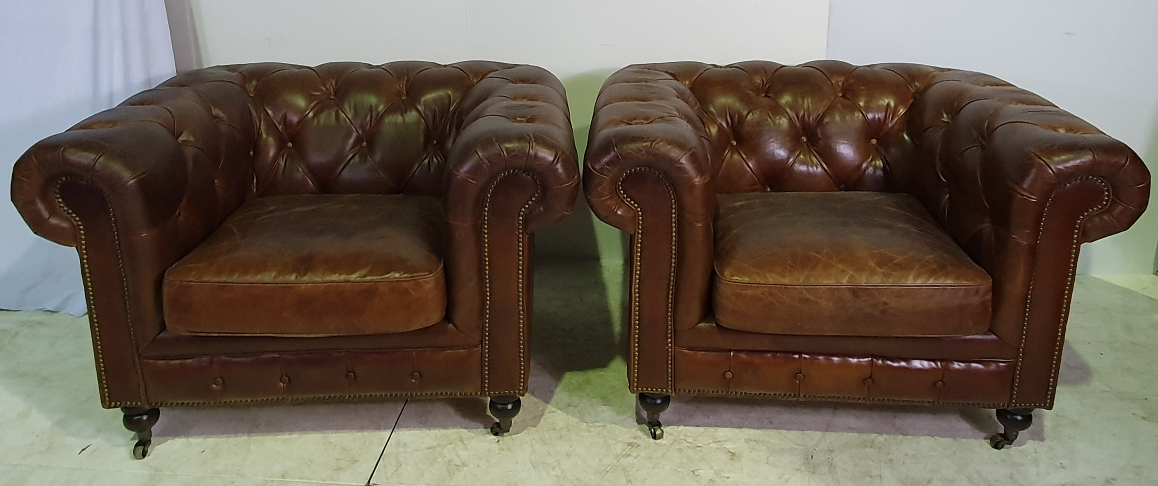 A GOOD QUALITY 20TH CENTURY PAIR OF LEATHER HIDE CHESTERFIELD ARMCHAIRS, with button back and roll