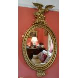 AN EARLY 19TH CENTURY GEORGIAN CARVED OVAL GILTWOOD MIRROR, with eagle surmount on a rocky base over