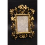 A TABLE TOP GILT FRAME / MIRROR, with raised foliage decoration, 12" x 8" approx frame