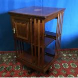 A MAHOGANY INLAID REVOLVING BOOKCASE with shelves and a small inlaid 1 door cabinet, 47cm x 47cm x