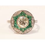 AN ART DECO STYLE EMERALD AND DIAMOND TARGET RING, with an 18CT white gold band, a centre diamond of