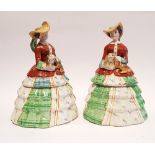 A PAIR OF CERAMIC JARS in the form of two ladies in dress and holding a dog in their arms