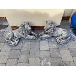A PAIR OF STONE RECLINING LION GARDEN ORNAMENTS, 65cm long approx.