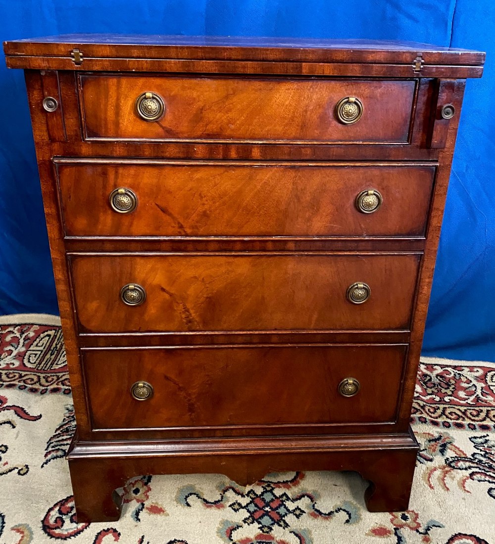 A MAHOGANY ‘BATCHELOR’ CHEST, with fold out top, over a short drawer, over 3 further drawers, raised