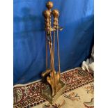 A 4 PIECE BRASS FIRE IRON SET, on stand, 74cm tall approx