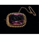 A 15CT YELLOW GOLD ANTIQUE AMETHYST & SEED PEARL BROOCH, complete with safety chain, the amethyst is