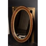 AN EDWARDIAN PARCEL GILT OVAL MIRROR, with bevelled glass, 108cm high x 76cm wide