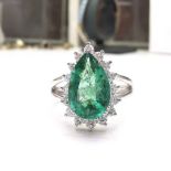 AN 18CT WHITE GOLD EMERALD & DIAMOND RING, with central tear drop shaped emerald, surrounded by