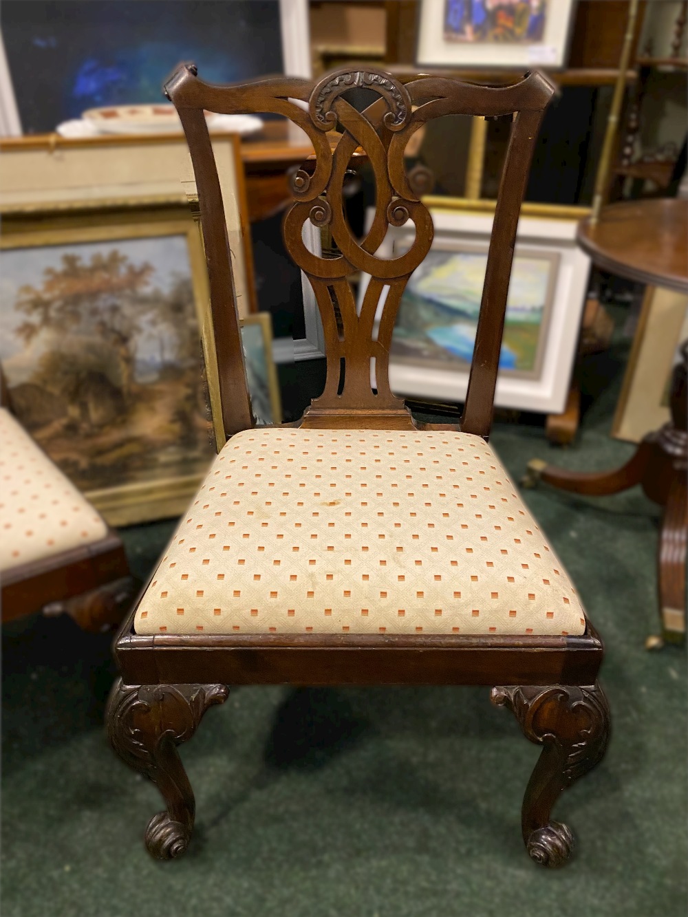 A PAIR OF GEORGE II CHAIRS, with carved back splats standing on carved cabriole legs and scroll
