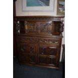 A reproduction carved oak court cupboard with central cupboard in canopy and drawers and cupboards