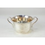 A George V silver two-handled cup, circular shape with hammered decoration and beaded scroll