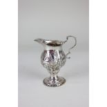 A George III silver cream jug, with scroll handle and possibly later floral embossed decoration,