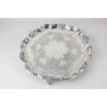 A Victorian silver salver with shell and scroll pie crust border and engraved decoration, on three
