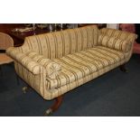 A Regency style upholstered settee, with scroll arms, squab cushion and two matching bolster