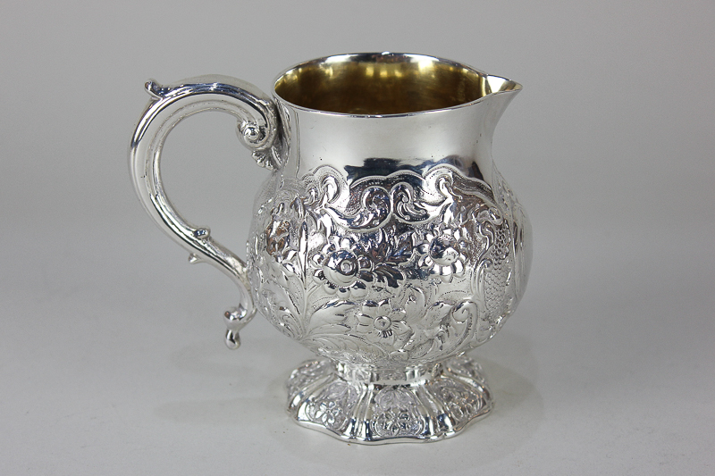 A Scottish silver cream jug with embossed floral decoration, gilt interior and scroll handle, 6oz,