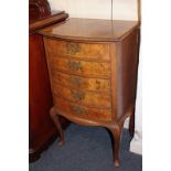 A walnut bowfront music cabinet of five drawers with dropped down hinged fronts, on stepped base and