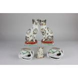 A pair of Staffordshire pottery models of cats seated on rectangular cushion bases, 17.5cm high, and
