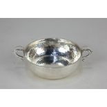 An Arts and Crafts Edward VII silver porringer dish, with two scroll handles and hammered