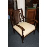 A bergere armchair, the back with cane work panel flanked by pierced supports with carved flower