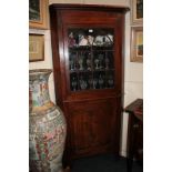 A Victorian inlaid mahogany corner cabinet, the glazed door enclosing three shelves above panel door