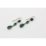A pair of emerald drop earrings loose hung with a chain of three mixed cut foil backed emeralds on