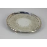A George III silver circular waiter with engraved scroll decoration and traces of a central