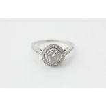 A diamond ring, the round brilliant cut stone set within a border of smaller stones, pave set