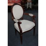 A Regency style elbow chair, with carved top rail, oval padded back, and open arms with scroll ends,