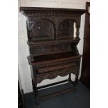 A small profusely carved oak dresser, the top section with two arches on turned uprights above a