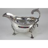 A George V silver sauce boat, oval shape with gadrooned border, flying scroll handle and three shell