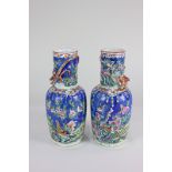 A pair of Chinese porcelain vases with overlaid dragon design, the bright design depicting birds