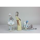 Three Lladro porcelain figures including a boy seated by a mile marker, a girl with a rabbit and a