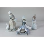 Three Lladro porcelain figures, including a seated girl with a duck and ducklings feeding on her
