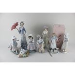 Three Lladro porcelain figures, a woman with a parasol, a girl with a mop and three cats and a