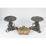 A pair of classical style bronzed metal dishes, each with scrolling tripod supports on triform base,